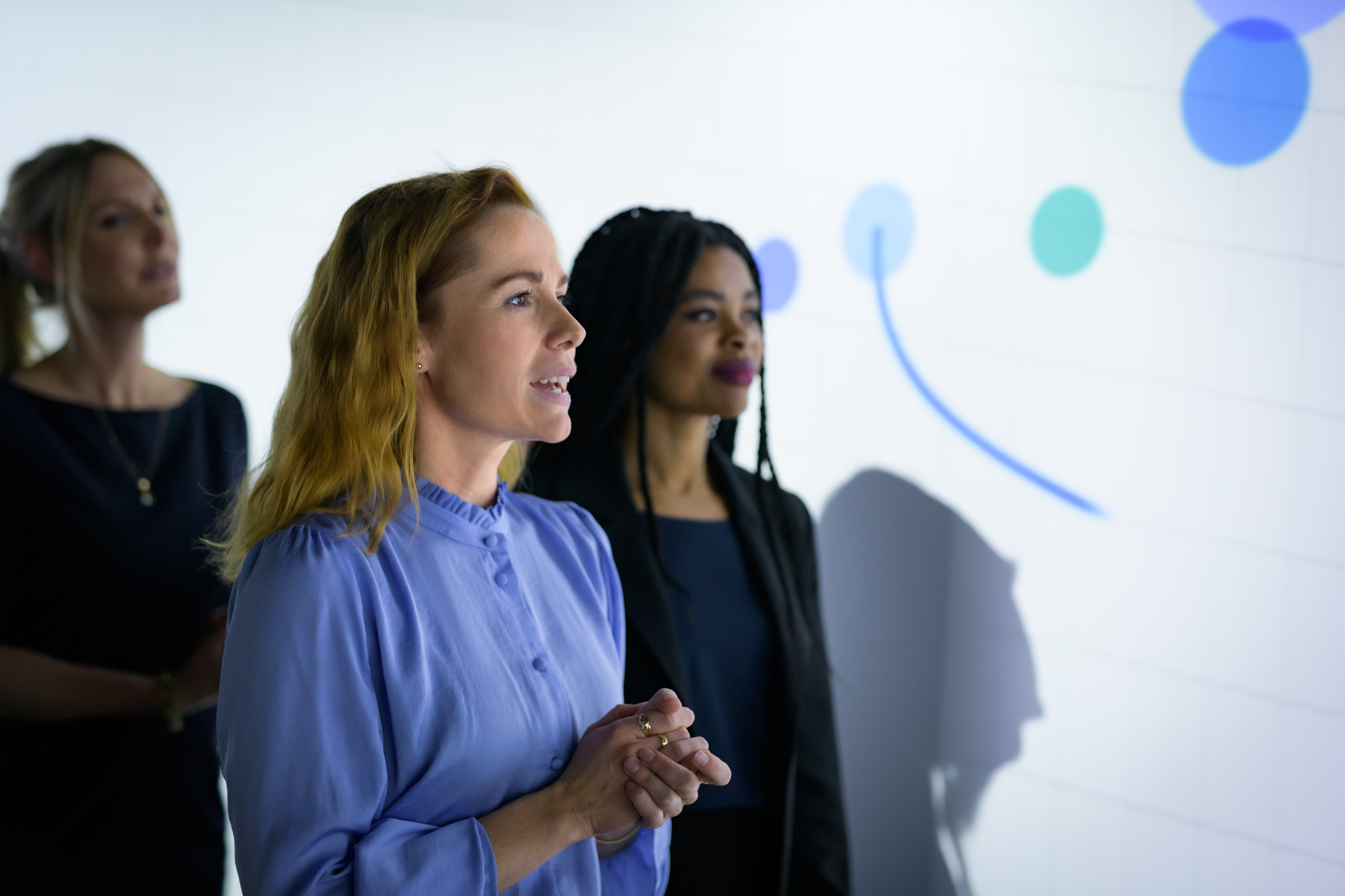 a group of women standing in front of a white board