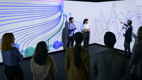 a group of people standing in front of a large screen