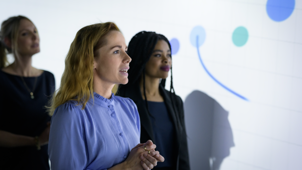 a group of women standing in front of a white board
