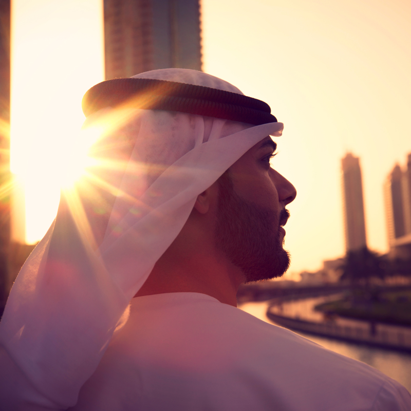 a person in a white robe and headdress looking out over a river