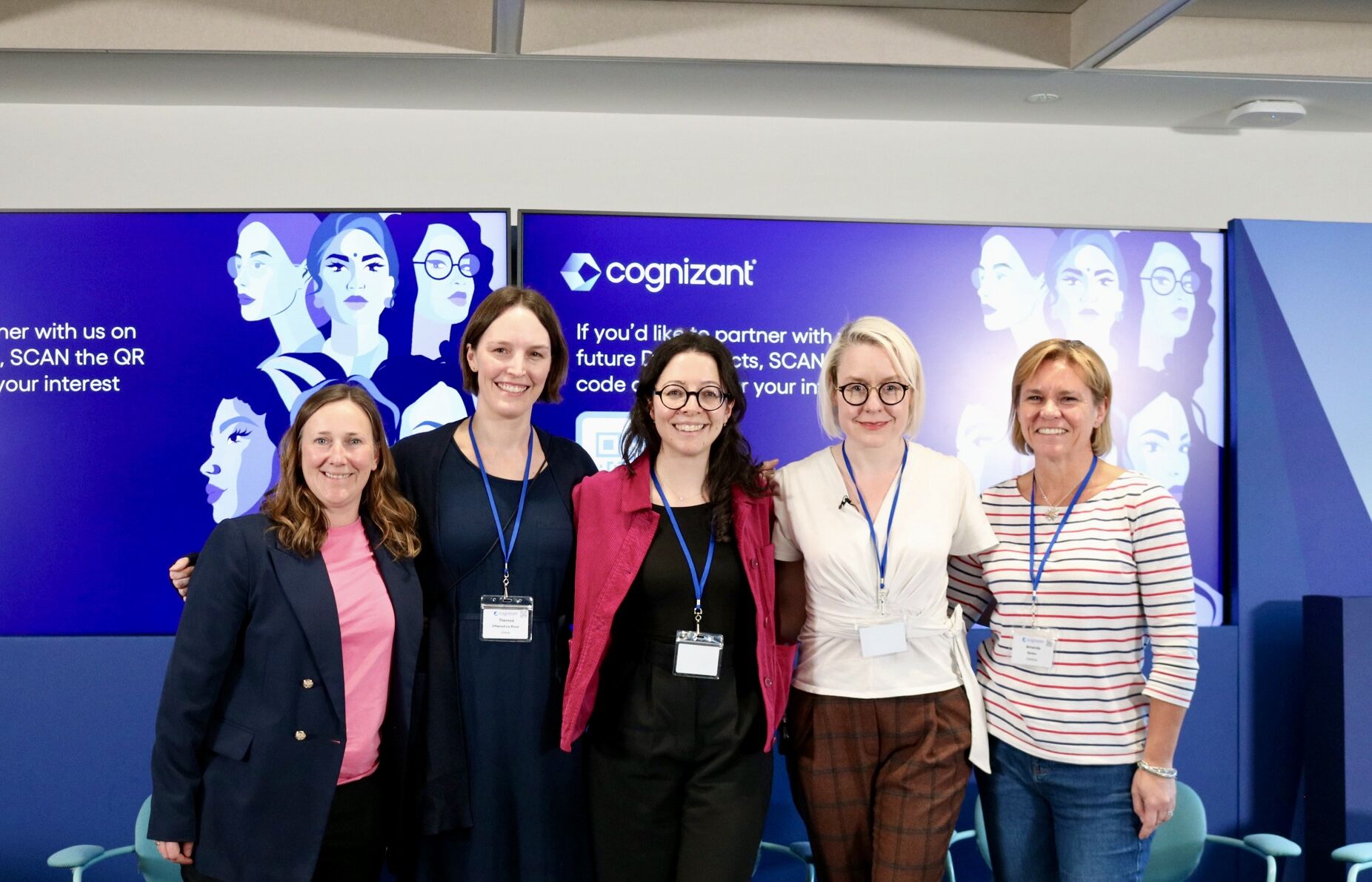 a group of women standing in front of a large poster