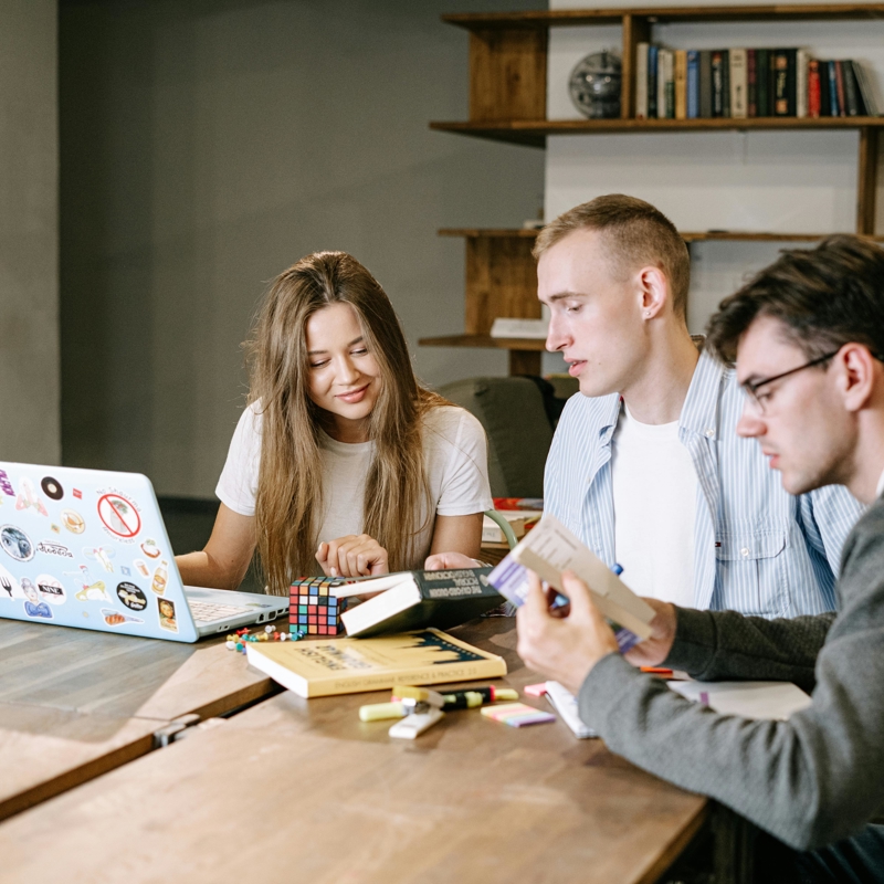 a group of people sitting at a table looking at a laptop
