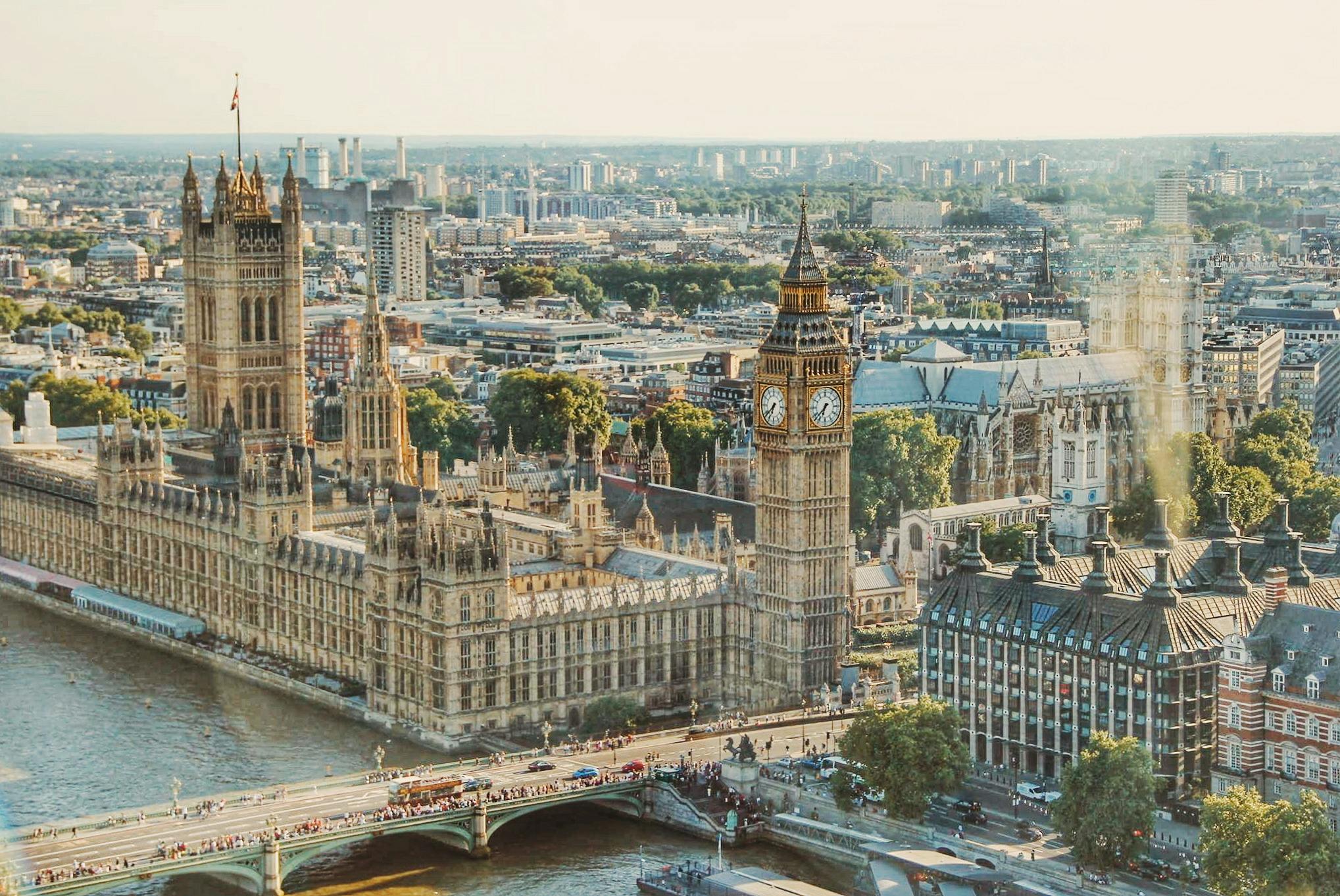a large building with a clock tower and Palace of Westminster over a river