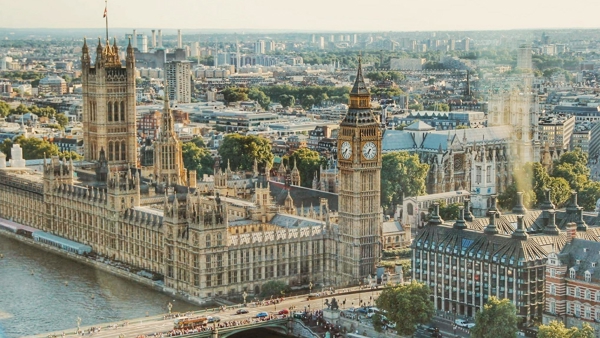 a large building with a clock tower and Palace of Westminster over a river