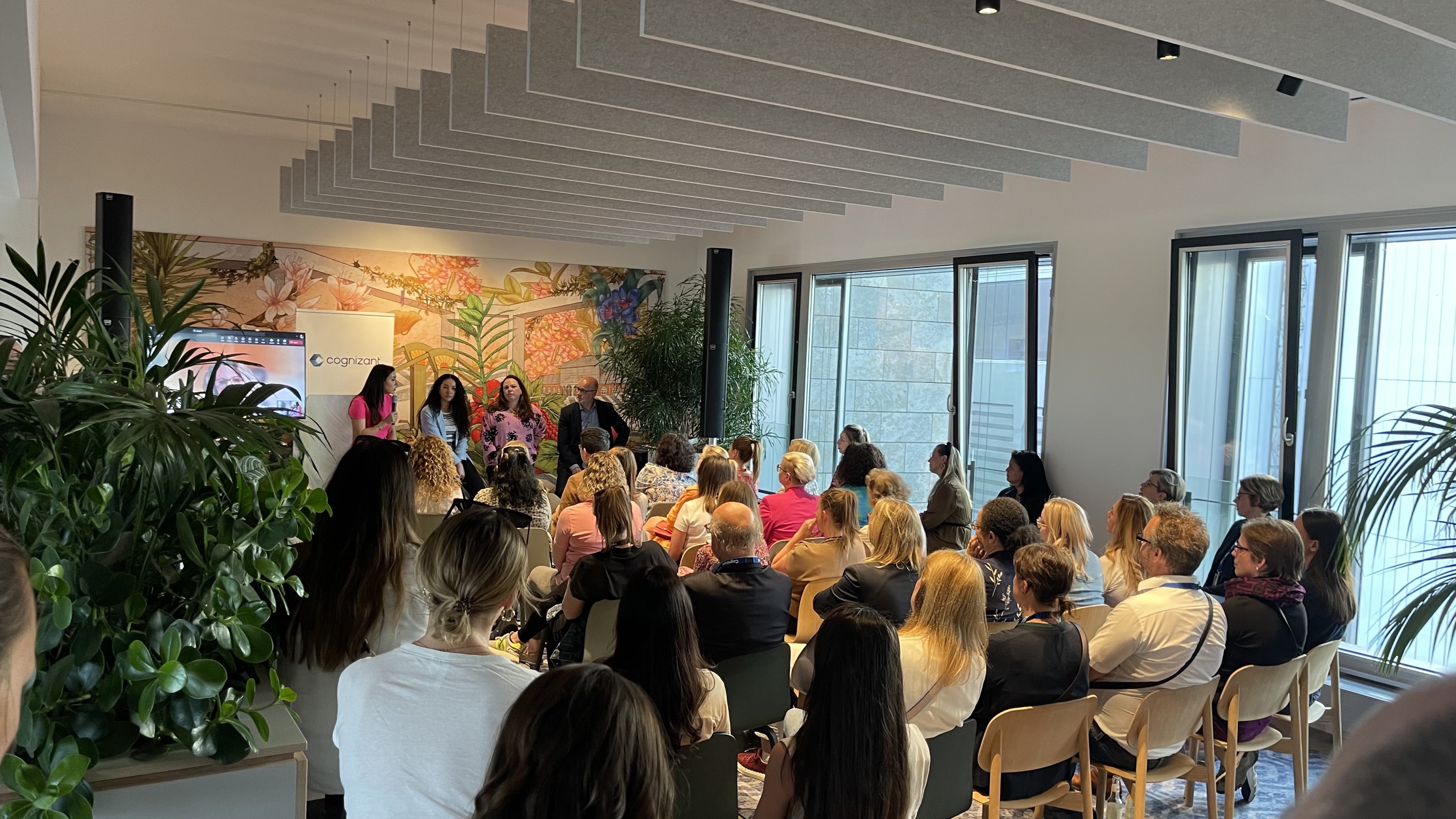 un groupe de personnes assises sur des chaises dans une pièce avec une personne debout devant un tableau blanc