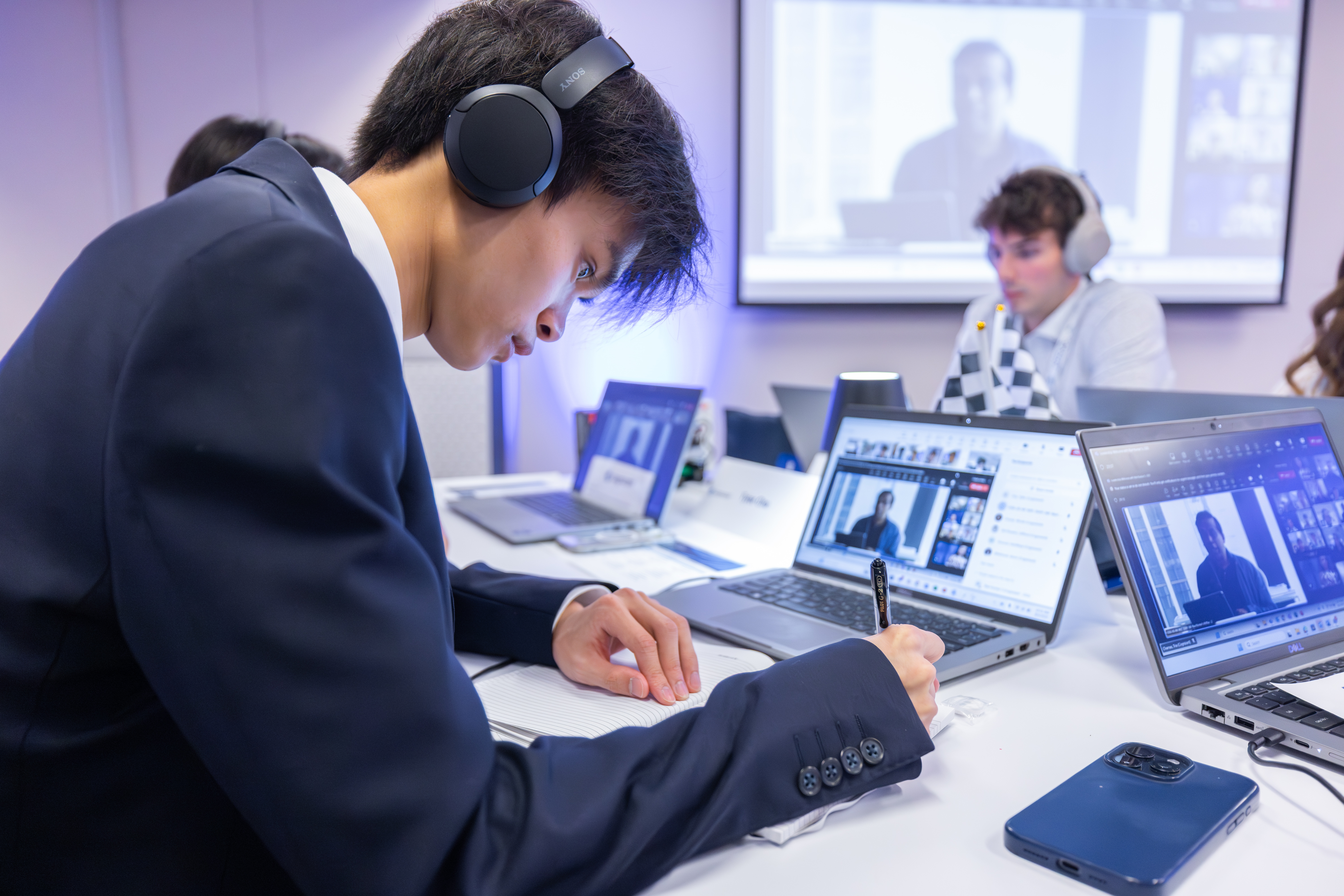 a person wearing headphones writing on a notebook