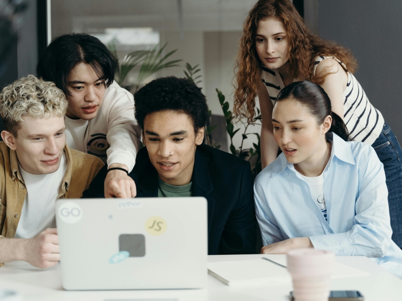 a group of people looking at a laptop