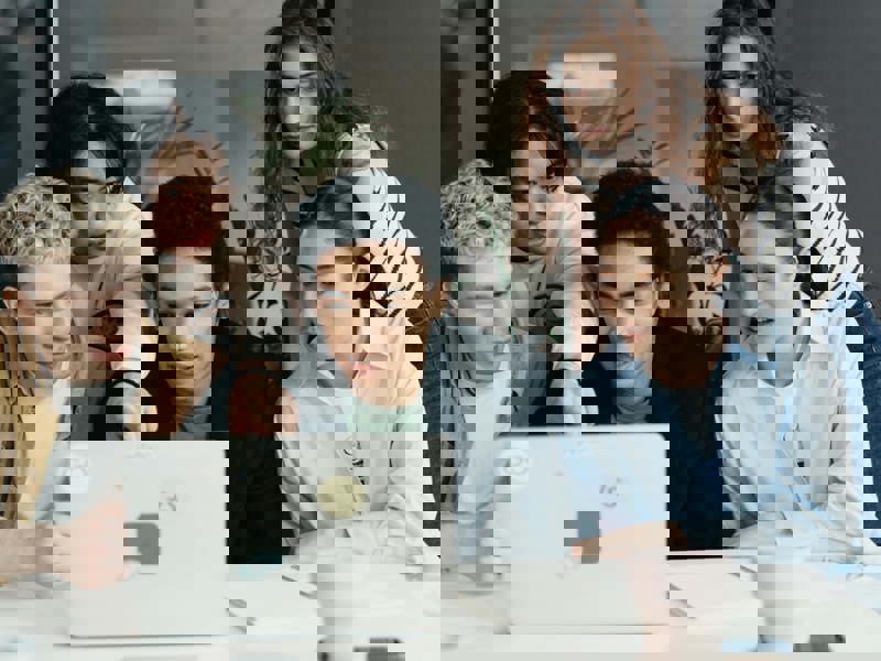 a group of people looking at a laptop