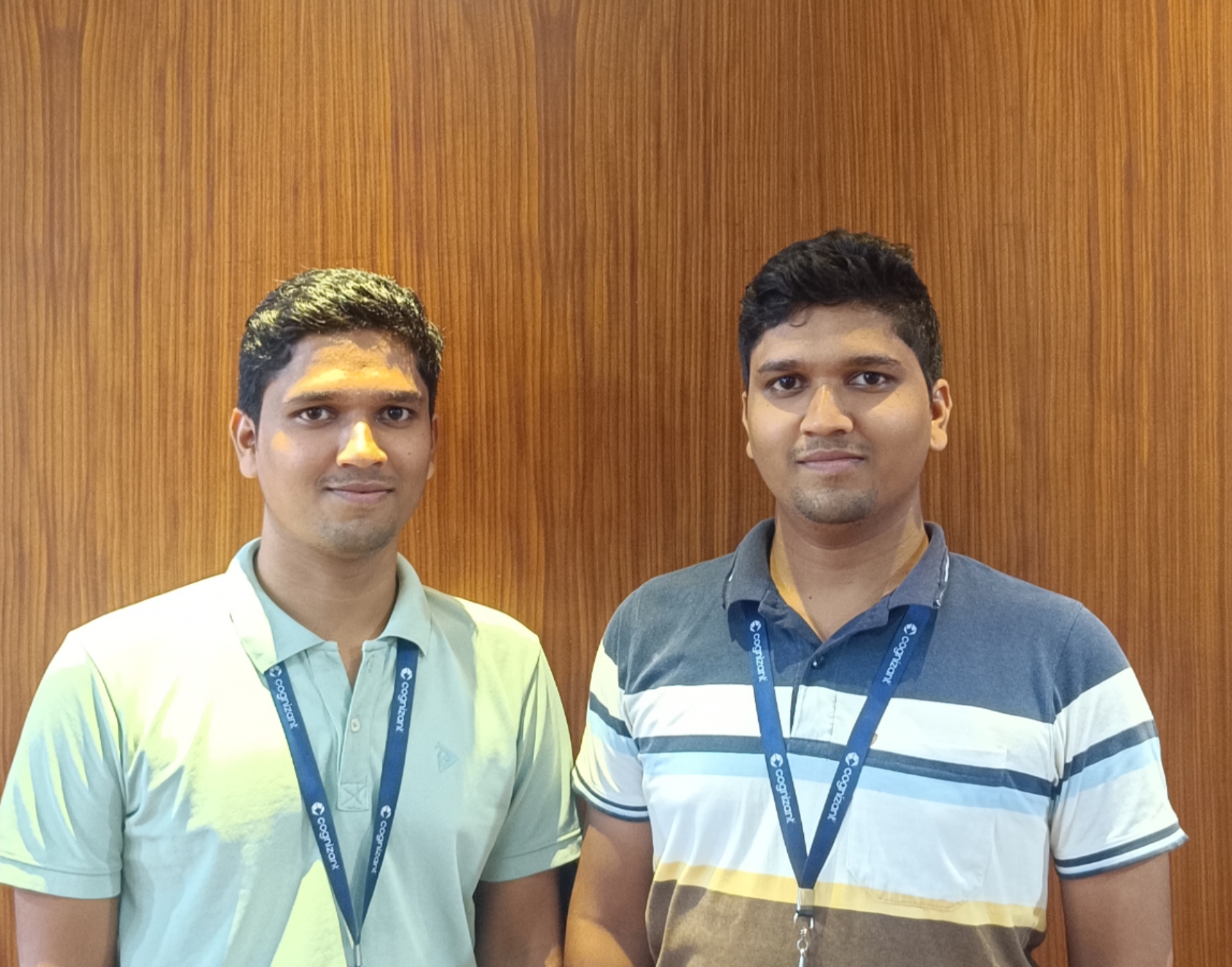 two men standing together in front of a wood wall