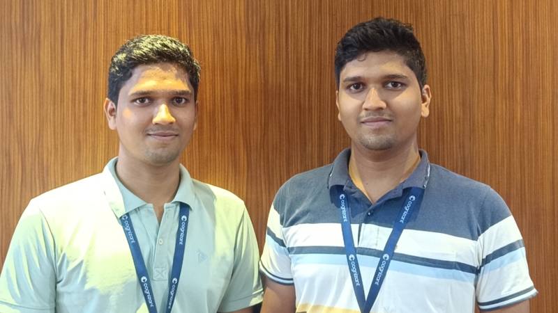 two men standing together in front of a wood wall
