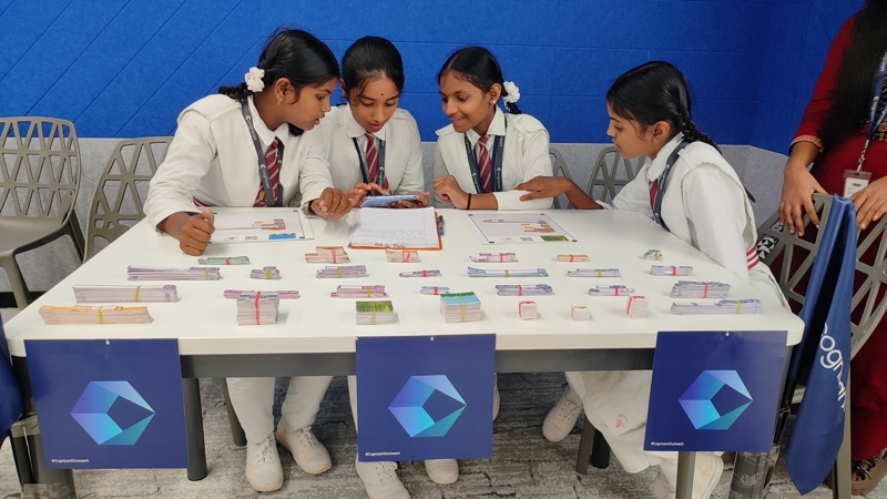 a group of childs sitting at a table with a table full of money