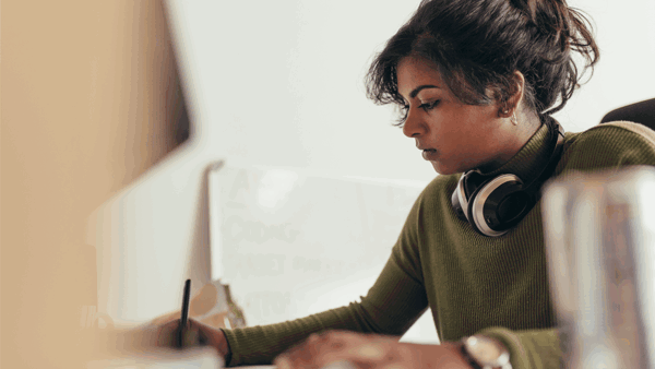 a person wearing headphones and writing on a paper