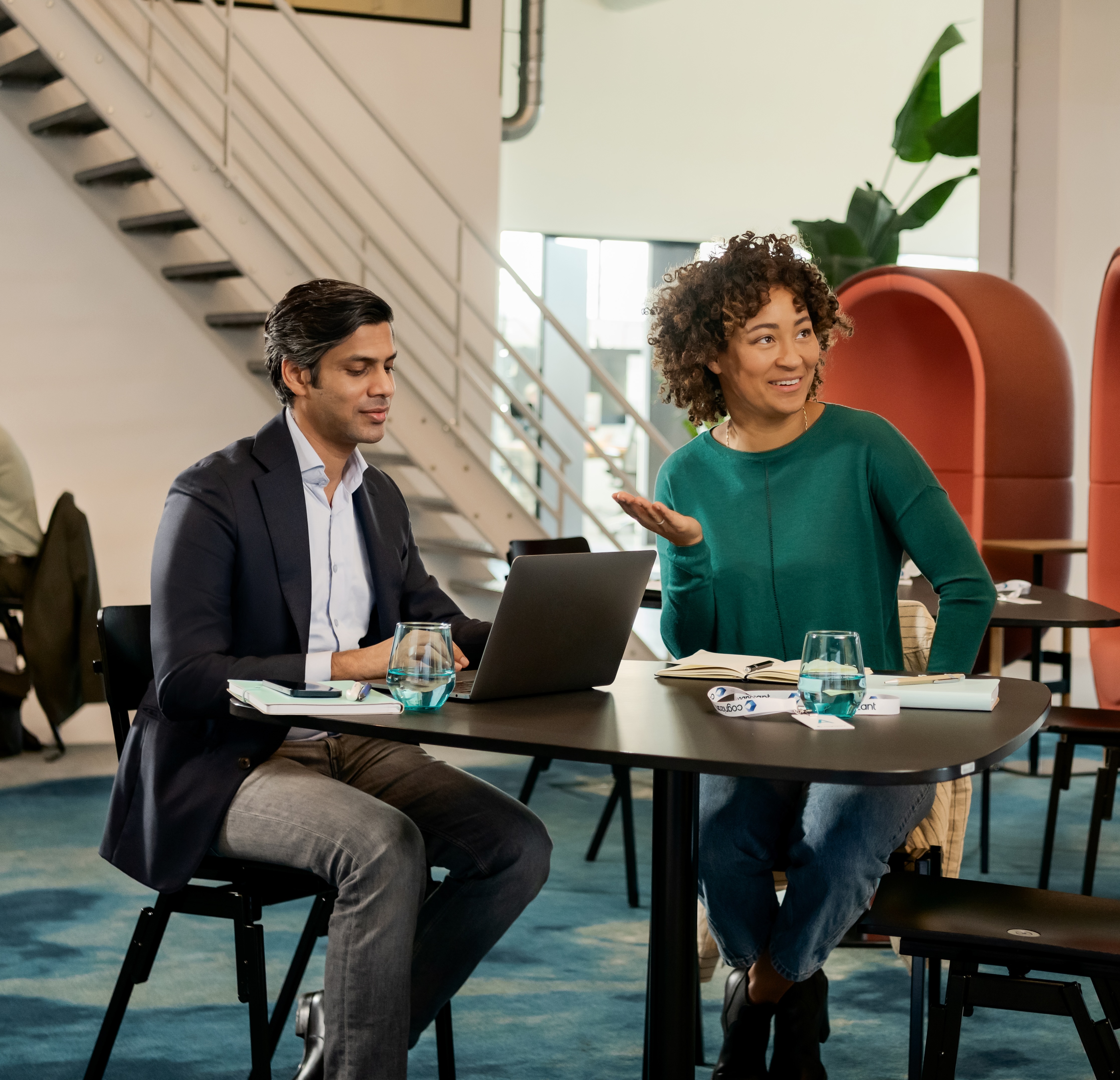 a person and person sitting at a table with a laptop