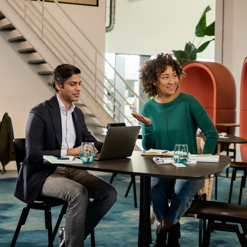 a person and person sitting at a table with a laptop