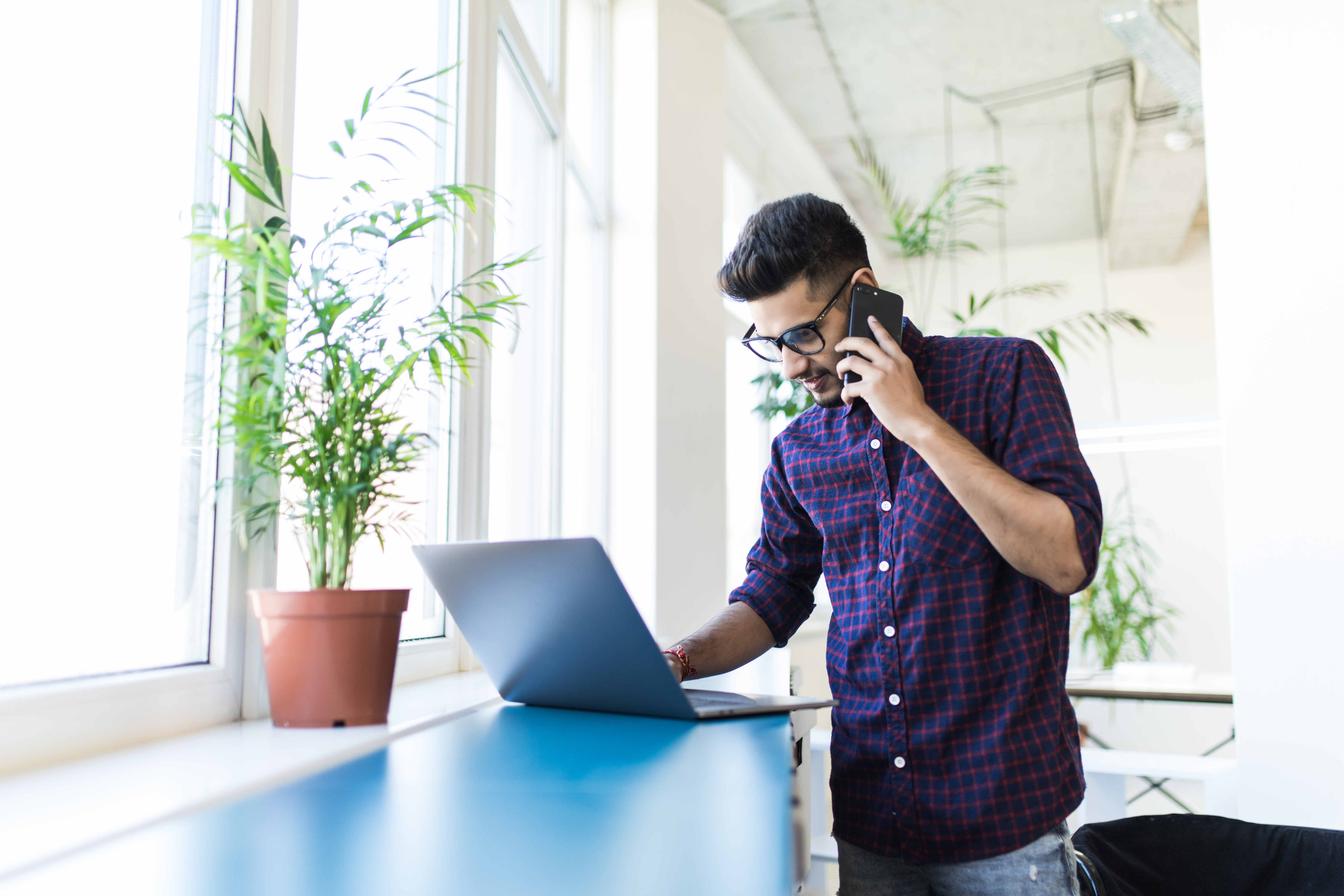 a person talking on a cell phone while using a laptop