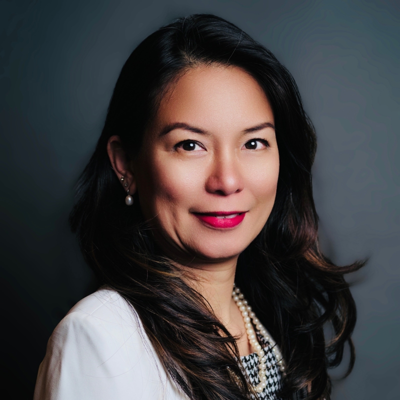 a person with long hair wearing a white shirt and pearl necklace