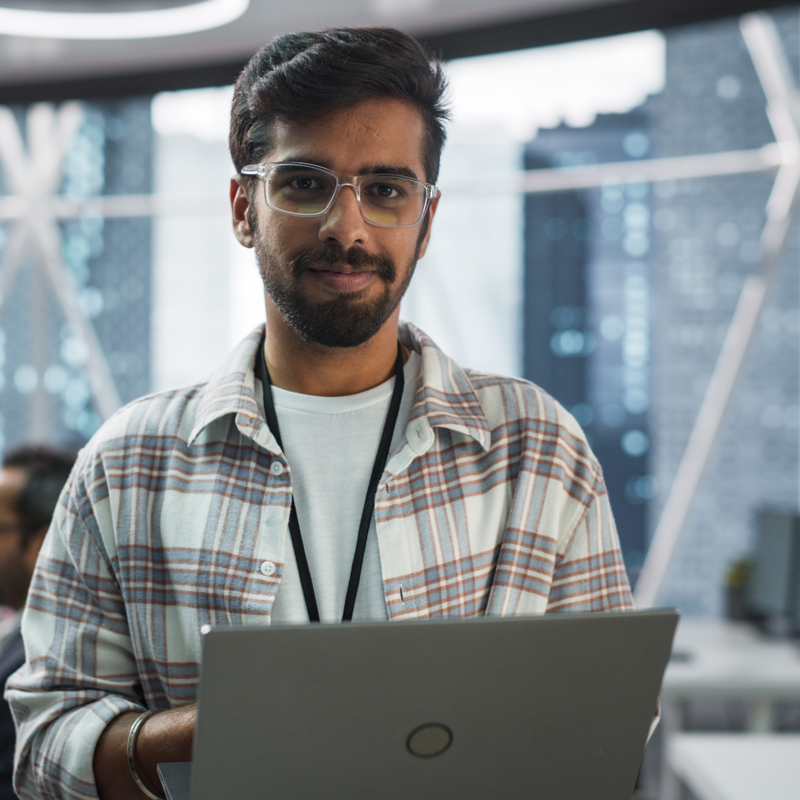 a person wearing glasses and a plaid shirt holding a laptop