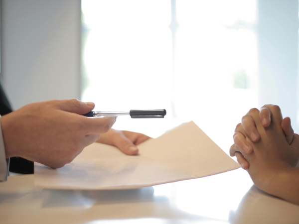 a person holding a pen over a paper