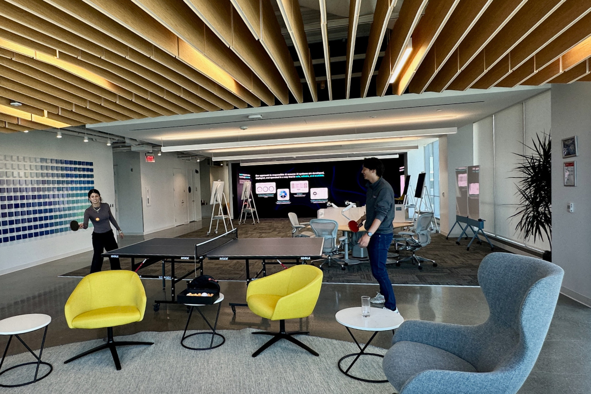 a person standing in a room with a ping pong table and chairs