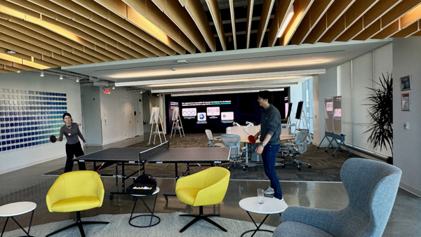 a person standing in a room with a ping pong table and chairs