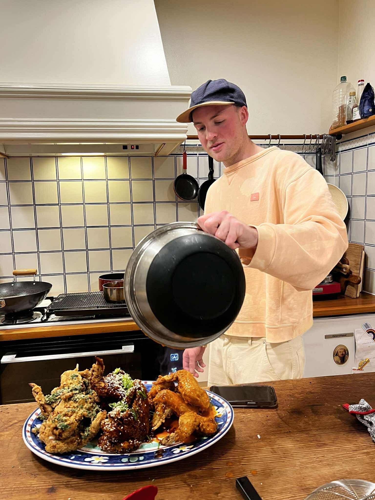 a person pouring a pan over a plate of chicken wings