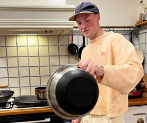 a person pouring a pan over a plate of chicken wings