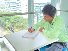 a person sitting at a table writing on a book