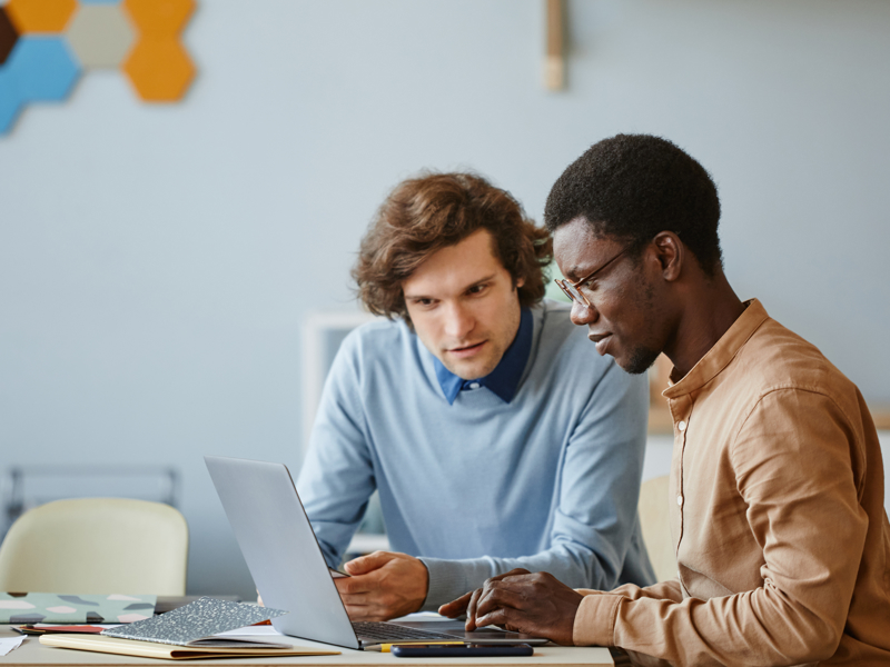 a group of men looking at a laptop