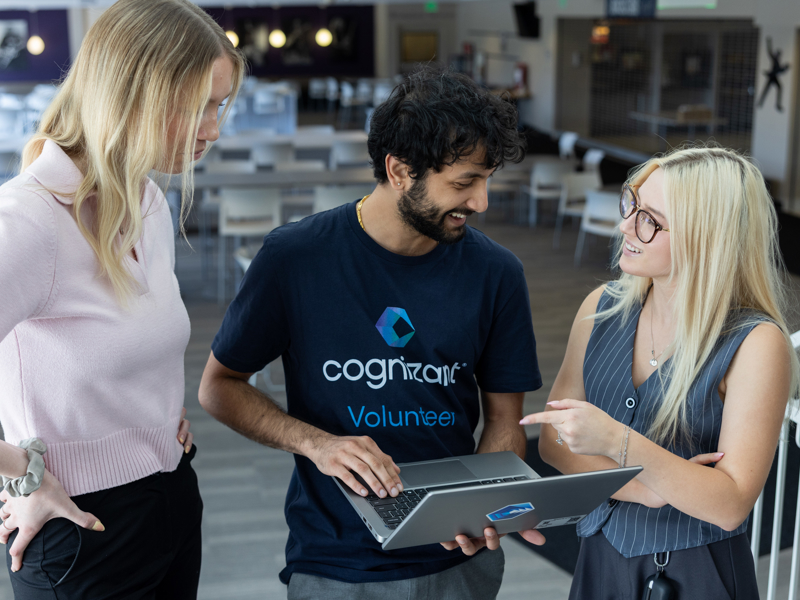 a group of people standing around a laptop