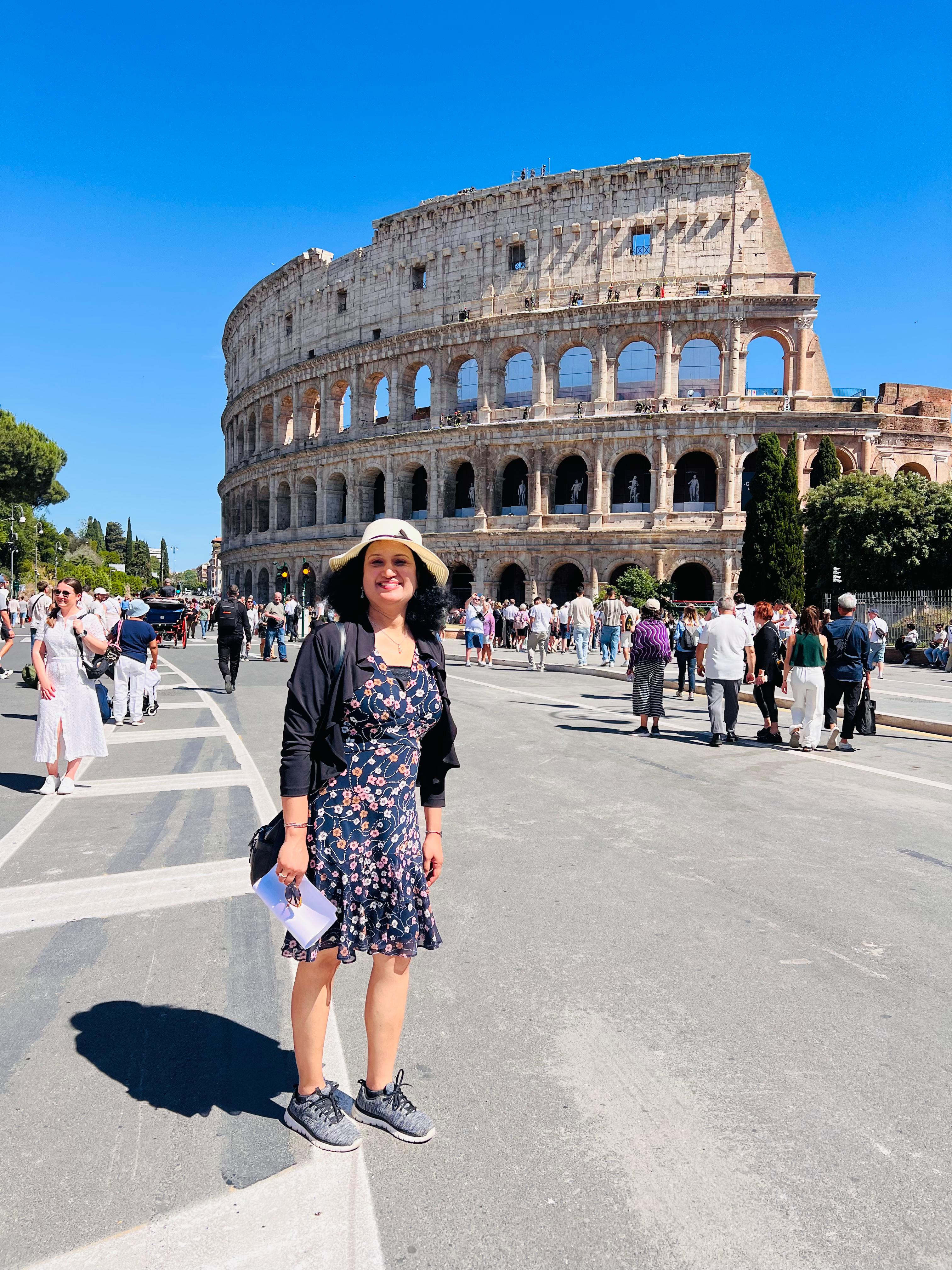 a person standing in front of a large stone colosseum