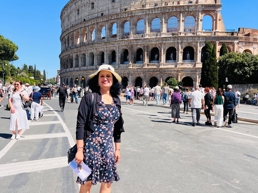a person standing in front of a large stone colosseum