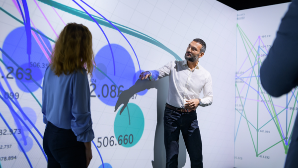 a person standing in front of a large screen with graphics on it