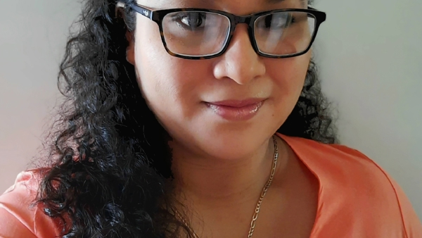 a person wearing glasses and a coral shirt