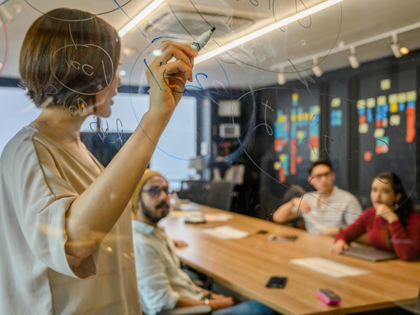 une personne écrivant sur un tableau de verre