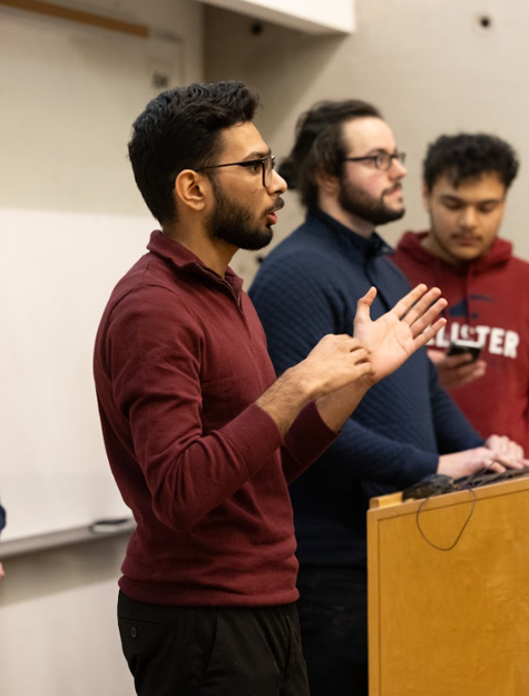 una persona de pie frente a un podio con otros hombres parados detrás de ella